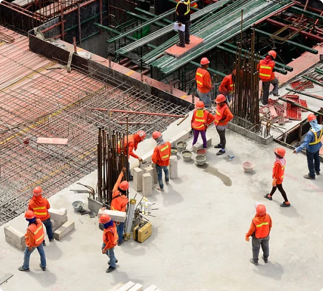 Low aerial view of construction workers on a job site, emphasizing teamwork in construction.